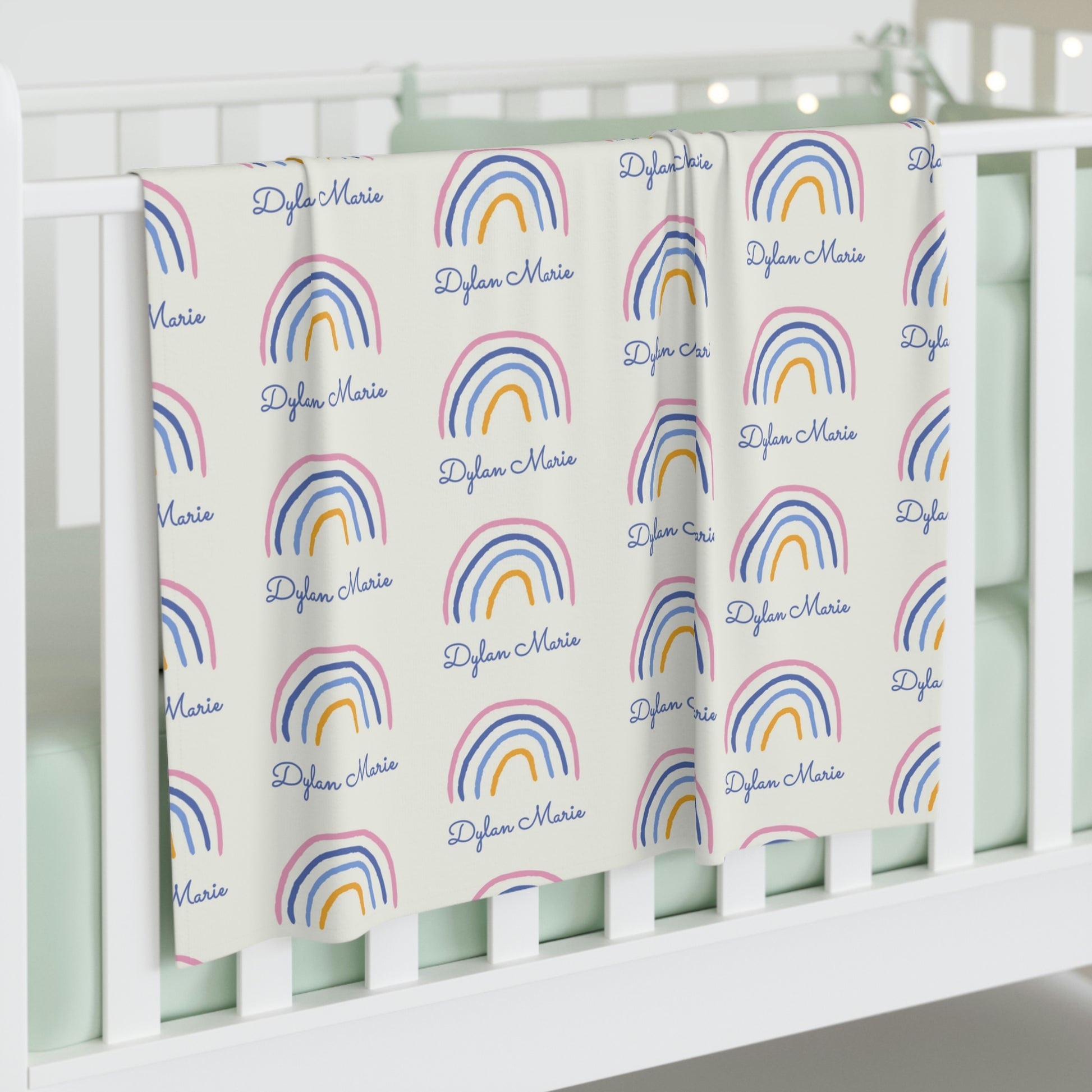 Jersey personalized baby blanket in rainbow pattern hung over side of white crib