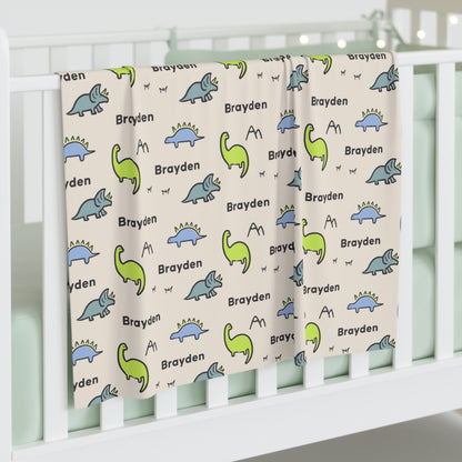 Jersey personalized baby blanket in dinosaur pattern hung over side of white crib