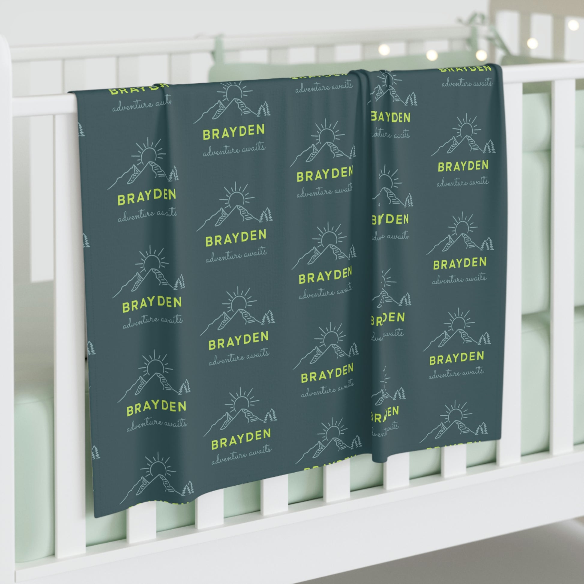 Jersey personalized baby blanket in green mountain adventure pattern hung over side of white crib