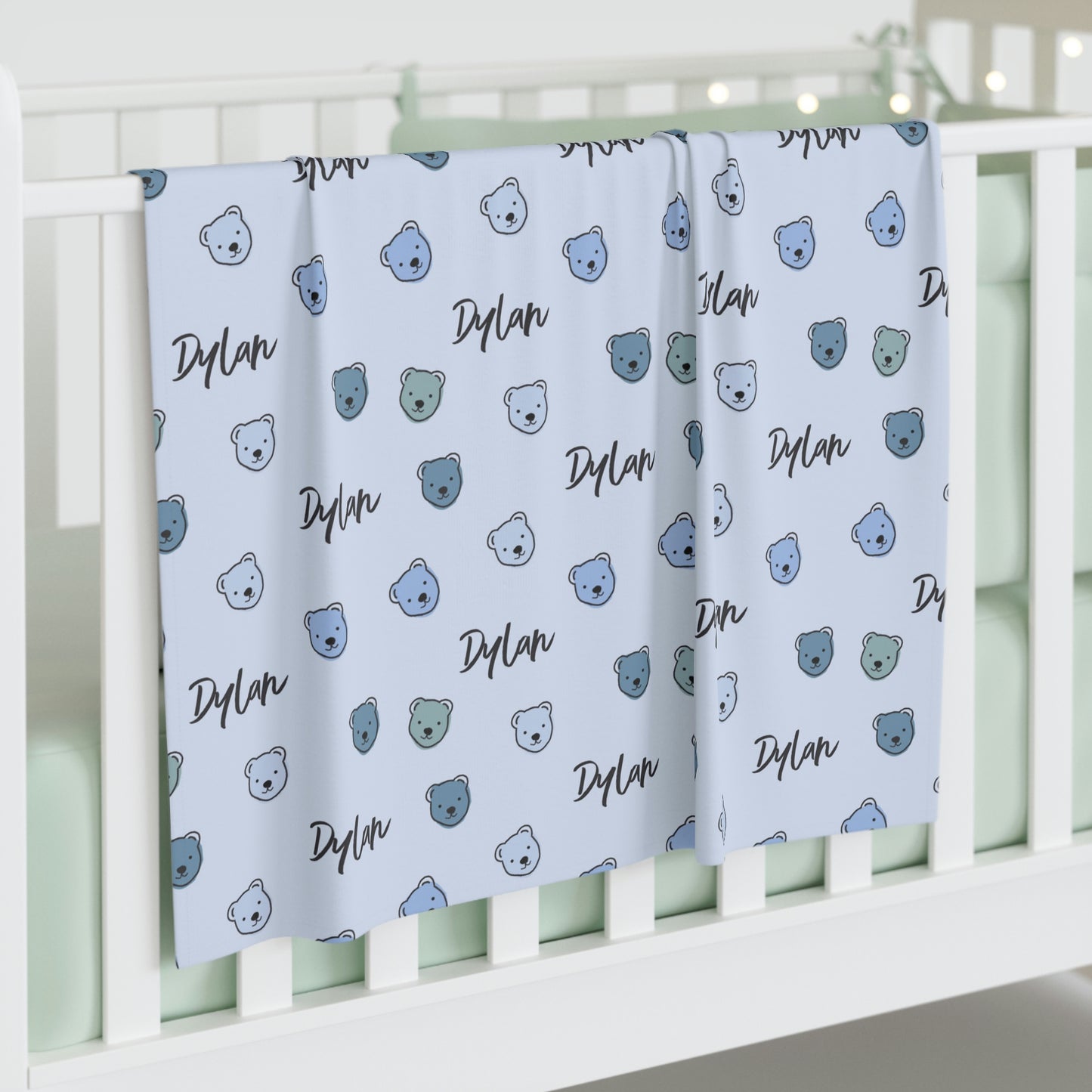 Jersey personalized baby blanket in blue cuddly bear pattern hung over side of white crib