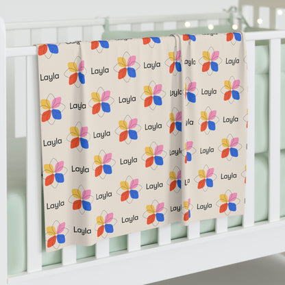 Jersey personalized baby blanket in a multi-colored geometric boho flower pattern hung over side of white crib