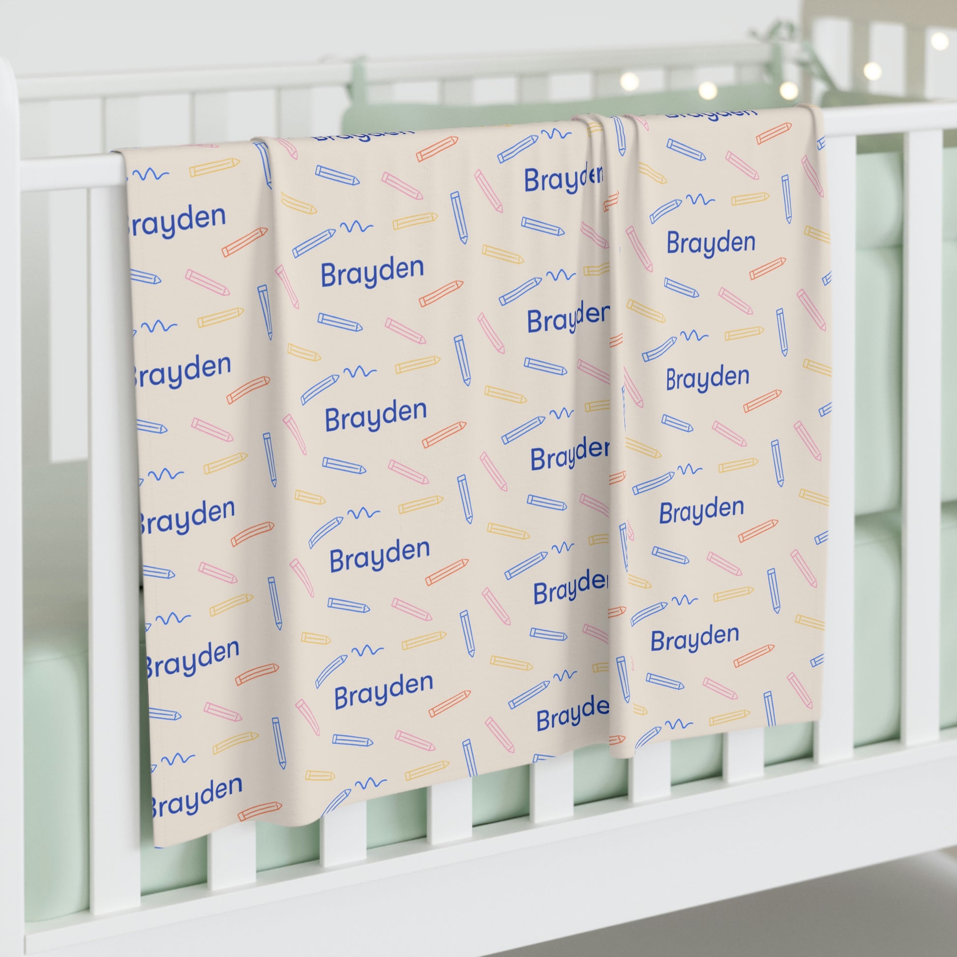 Jersey personalized baby blanket in colored pencil pattern hung over side of white crib