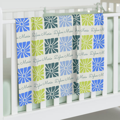 Jersey personalized baby blanket in boho blue flower pattern hung over side of white crib