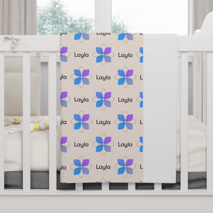 Fleece personalized baby blanket in blue boho geometric flower pattern hung over side of white crib with window in the background