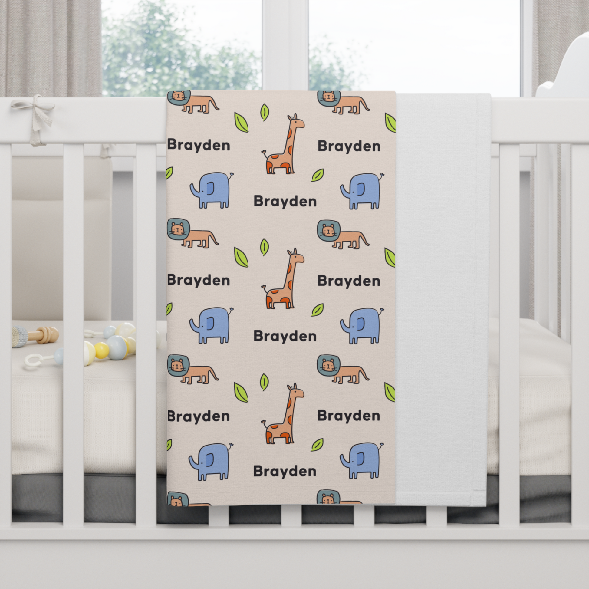Fleece personalized baby blanket in safari animal pattern hung over side of white crib with window in the background