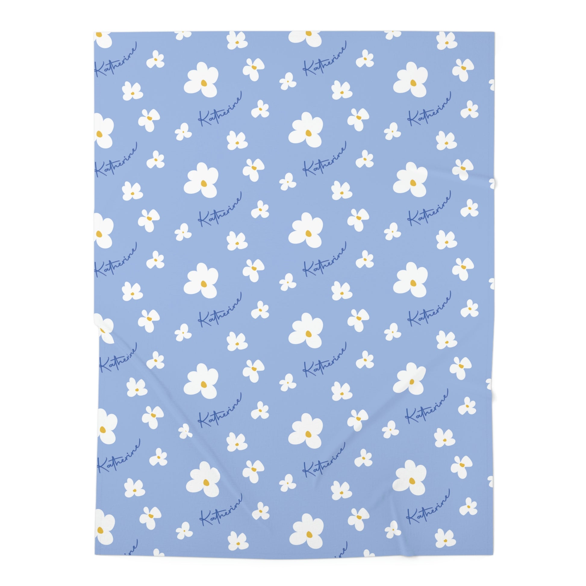 Jersey personalized baby blanket in blue daisy pattern hung over side of white crib