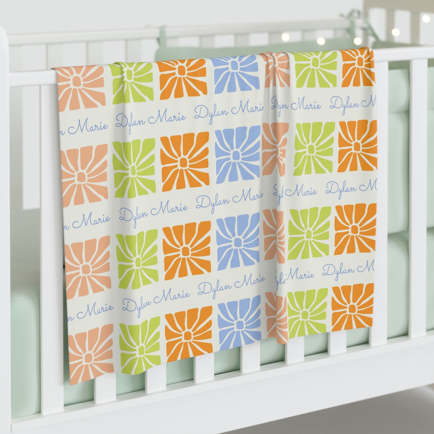 Jersey personalized baby blanket in a multi-colored boho flower pattern hung over side of white crib